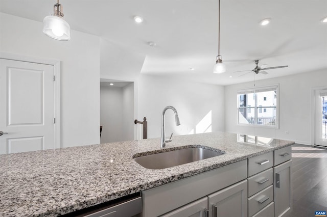 kitchen with sink, decorative light fixtures, ceiling fan, and light stone countertops