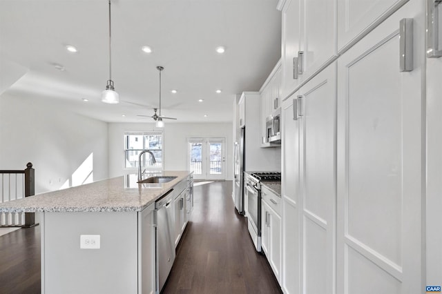 kitchen with appliances with stainless steel finishes, white cabinets, a kitchen island with sink, and sink