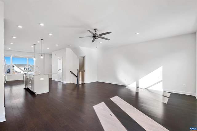 unfurnished living room featuring dark wood-type flooring, ceiling fan, and sink