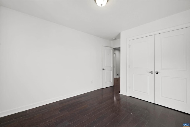 unfurnished bedroom with a closet and dark hardwood / wood-style floors