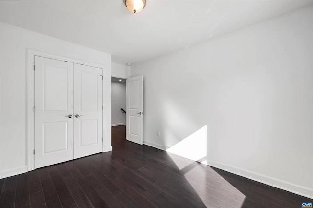 unfurnished bedroom with a closet and dark hardwood / wood-style floors