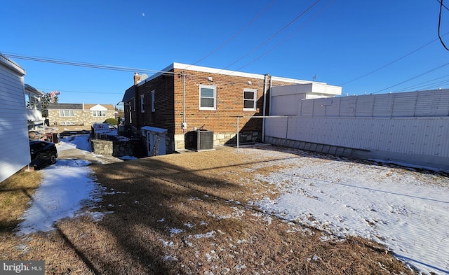 snow covered rear of property with central AC unit