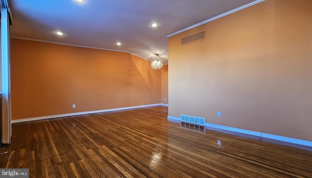 empty room featuring dark hardwood / wood-style floors, crown molding, and a notable chandelier