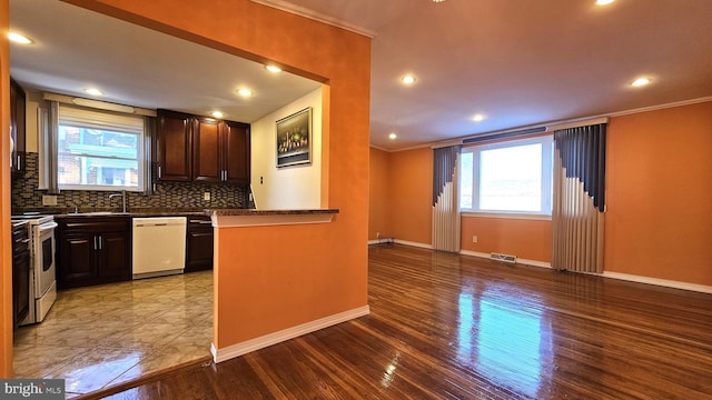 kitchen with decorative backsplash, white dishwasher, plenty of natural light, and stainless steel range oven