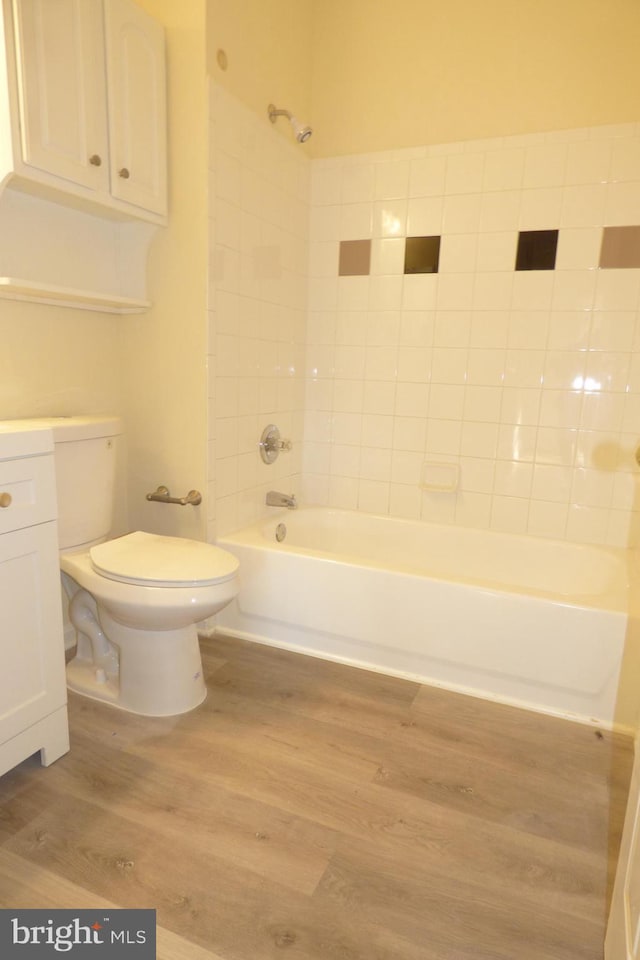 full bathroom with vanity, hardwood / wood-style floors, tiled shower / bath combo, and toilet