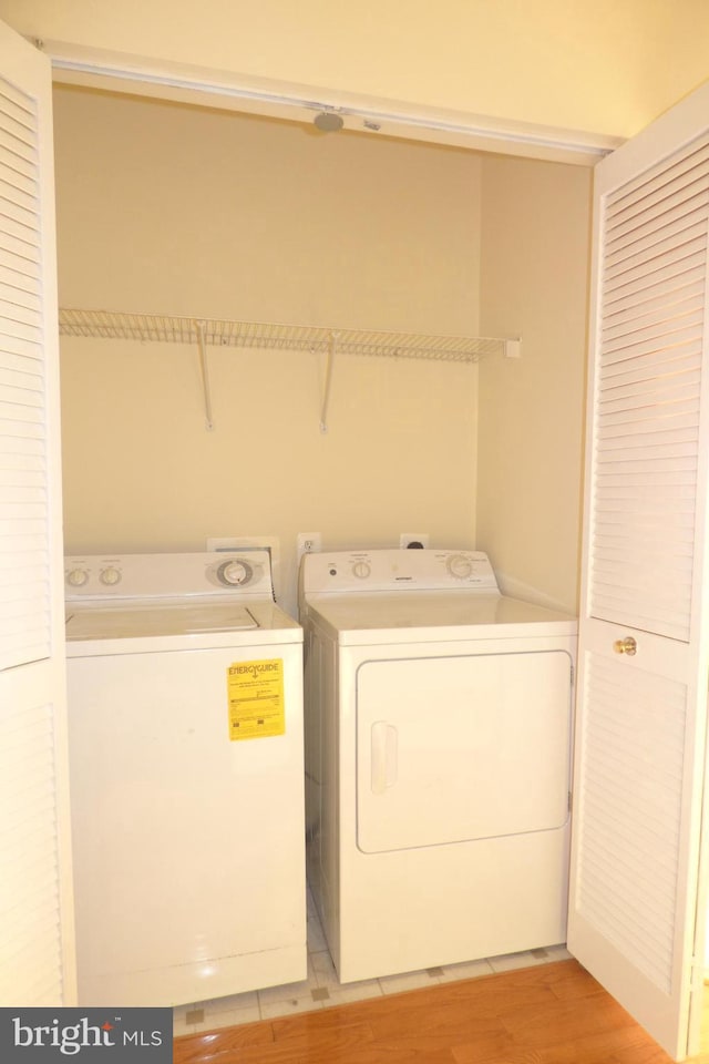 laundry area with light hardwood / wood-style flooring and washing machine and dryer