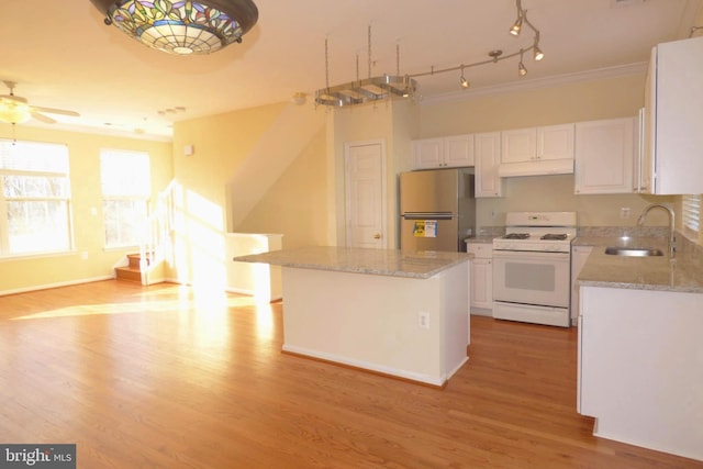 kitchen featuring sink, stainless steel refrigerator, white range with gas stovetop, white cabinetry, and a kitchen island