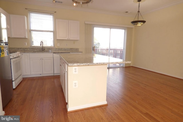 kitchen with pendant lighting, white cabinetry, sink, a center island, and white appliances