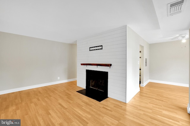 unfurnished living room with a large fireplace, light hardwood / wood-style floors, and ceiling fan