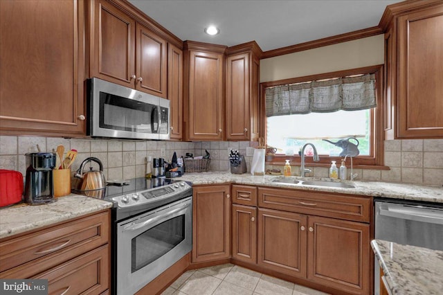 kitchen featuring backsplash, light stone counters, ornamental molding, stainless steel appliances, and sink