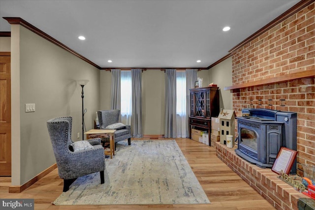 sitting room featuring light hardwood / wood-style floors, a wood stove, and crown molding