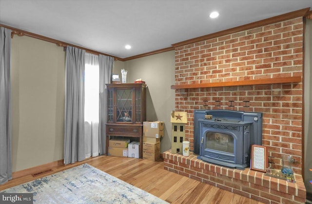 living room featuring hardwood / wood-style floors, a wood stove, and crown molding