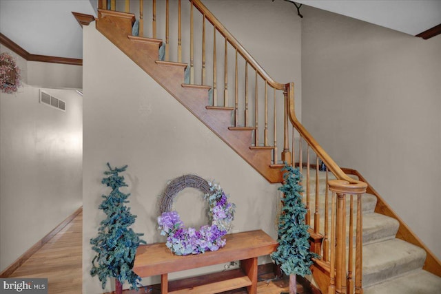 staircase with hardwood / wood-style floors and crown molding