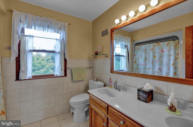 bathroom with tile patterned flooring, vanity, toilet, and tile walls