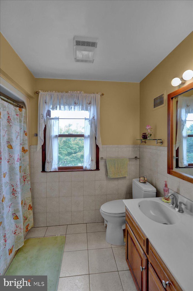 bathroom featuring toilet, vanity, tile patterned floors, and tile walls