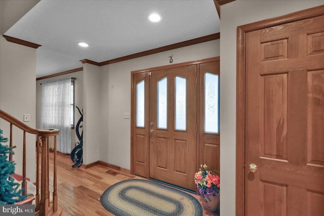 foyer entrance featuring crown molding, a healthy amount of sunlight, and light wood-type flooring