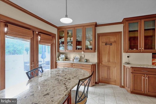 kitchen featuring a kitchen breakfast bar, light stone countertops, crown molding, and hanging light fixtures