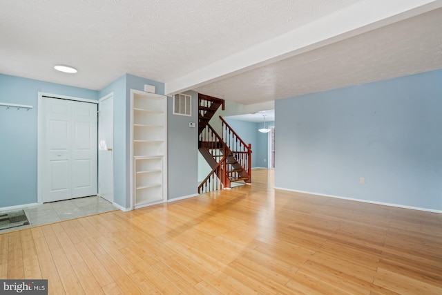 unfurnished room featuring beamed ceiling, a textured ceiling, and hardwood / wood-style flooring