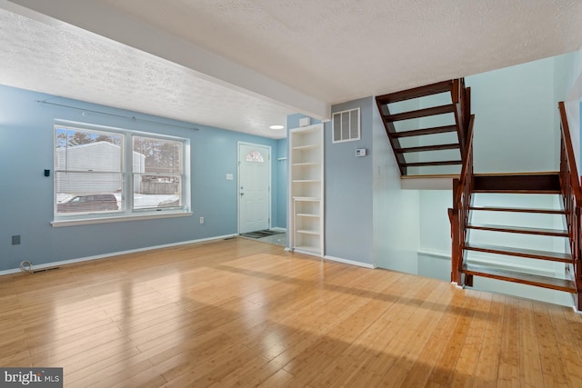 unfurnished living room with hardwood / wood-style floors and a textured ceiling