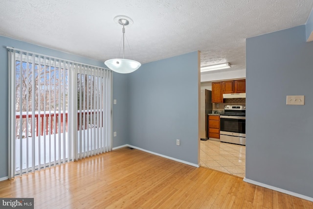 unfurnished dining area with light hardwood / wood-style floors and a textured ceiling