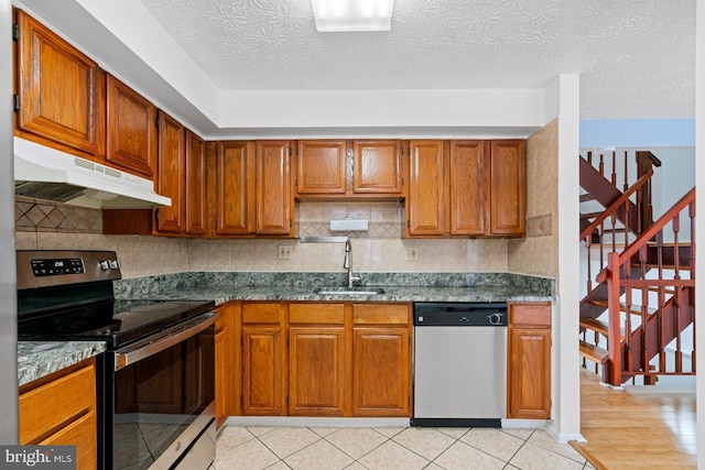 kitchen featuring a textured ceiling, light tile patterned flooring, sink, and appliances with stainless steel finishes