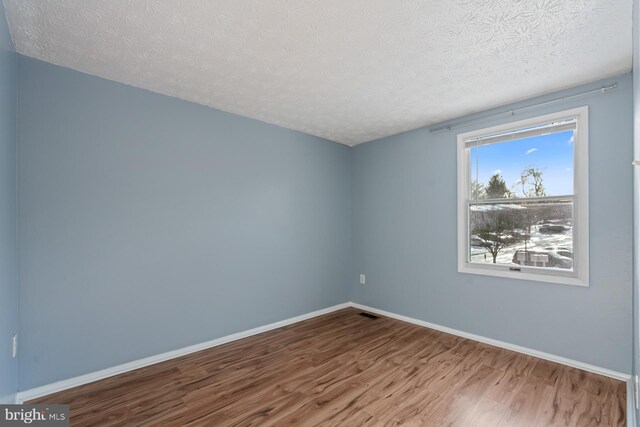 spare room with a textured ceiling and hardwood / wood-style flooring