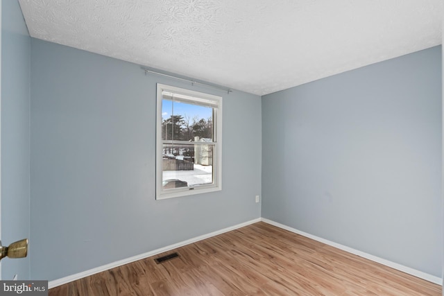 spare room featuring light hardwood / wood-style flooring and a textured ceiling