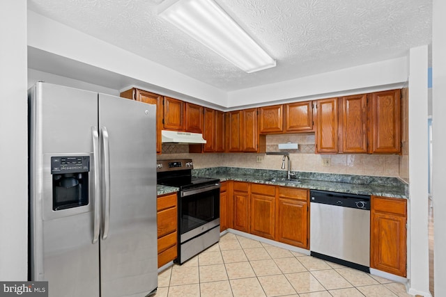 kitchen with a textured ceiling, light tile patterned floors, sink, and appliances with stainless steel finishes