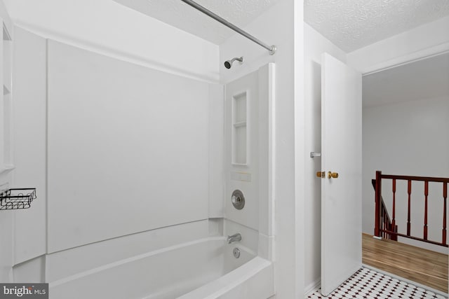 bathroom with shower / tub combination and a textured ceiling