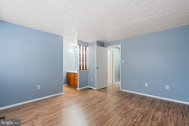 interior space with a textured ceiling, connected bathroom, and light hardwood / wood-style flooring