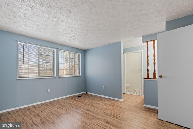 spare room with light hardwood / wood-style flooring and a textured ceiling