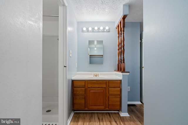 bathroom featuring hardwood / wood-style floors, vanity, a shower, and a textured ceiling