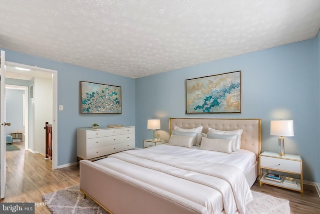 bedroom with a textured ceiling and light hardwood / wood-style floors