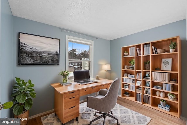 office area featuring light hardwood / wood-style floors and a textured ceiling