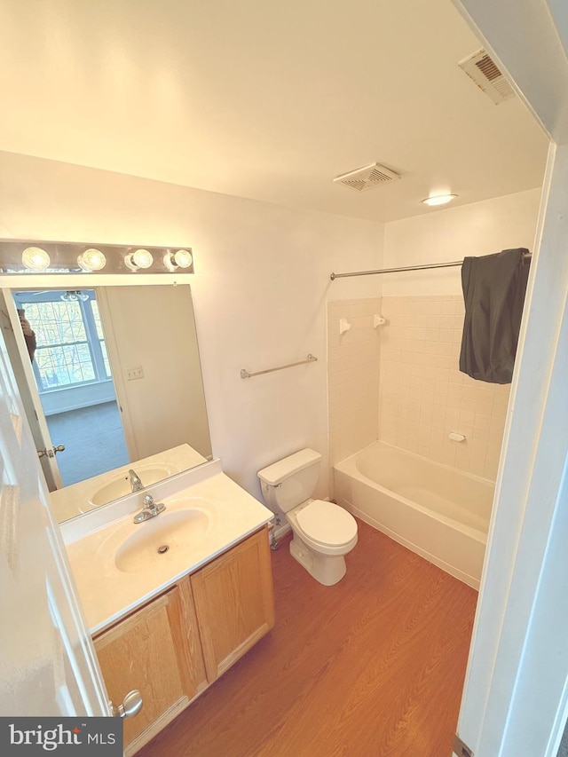 full bathroom featuring hardwood / wood-style flooring, toilet, vanity, and tiled shower / bath combo