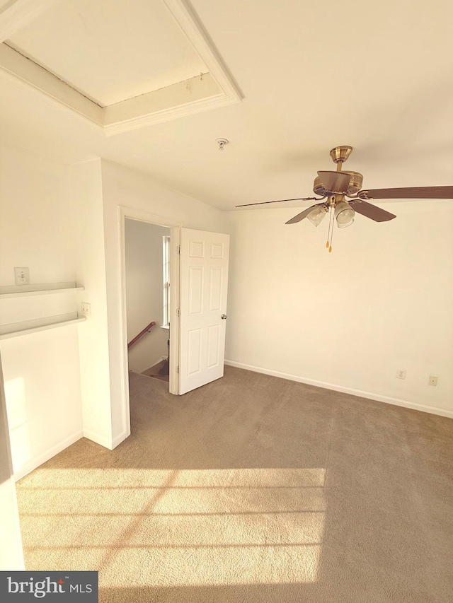 empty room featuring ceiling fan, carpet, and a tray ceiling