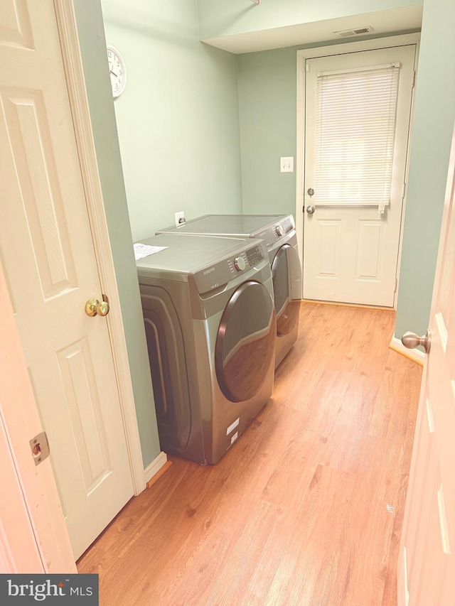 clothes washing area featuring independent washer and dryer and light hardwood / wood-style flooring