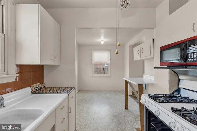 kitchen featuring sink, white gas range oven, white cabinetry, and backsplash