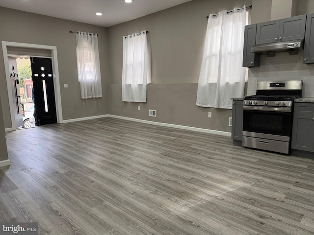 kitchen featuring gray cabinets, tasteful backsplash, light hardwood / wood-style floors, and gas range