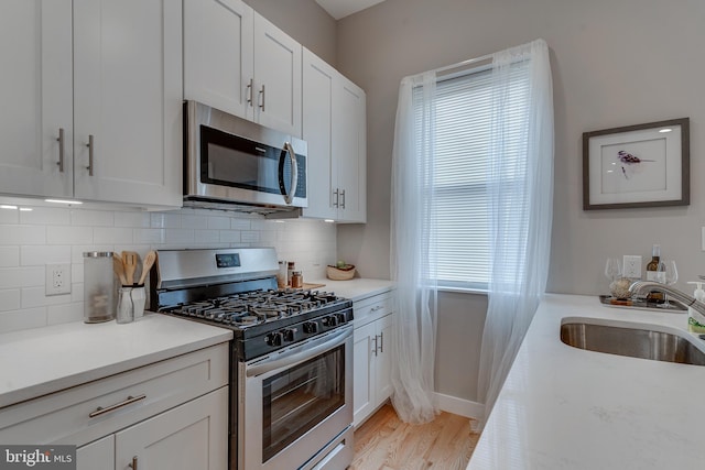 kitchen featuring white cabinetry, sink, a healthy amount of sunlight, backsplash, and appliances with stainless steel finishes