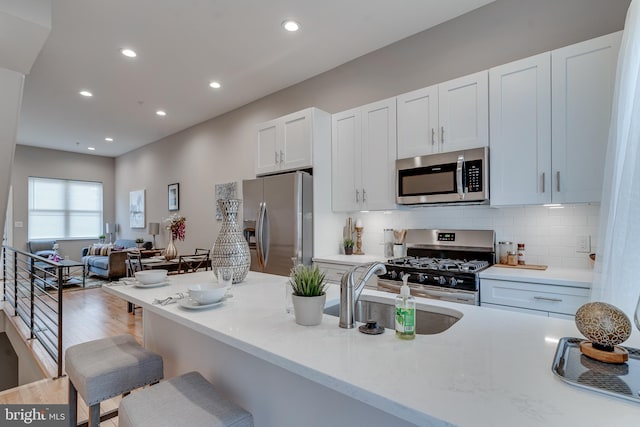 kitchen with appliances with stainless steel finishes, backsplash, white cabinetry, and sink