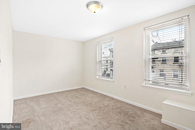 empty room featuring light carpet and baseboards