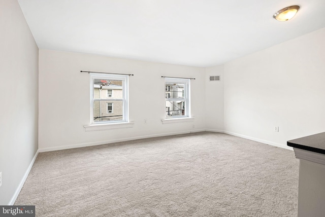 unfurnished room featuring carpet, visible vents, and baseboards