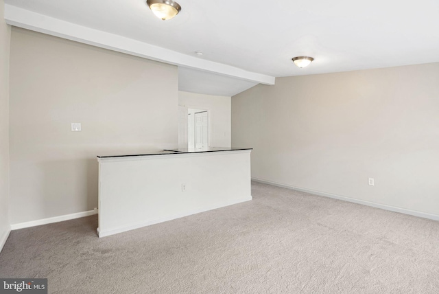 carpeted empty room featuring vaulted ceiling with beams and baseboards