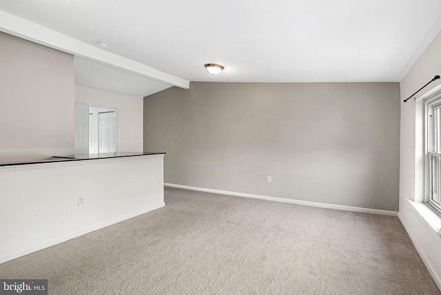 carpeted empty room featuring vaulted ceiling with beams and baseboards