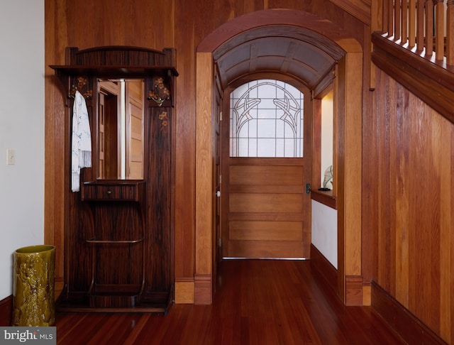 entryway with dark hardwood / wood-style floors and wooden walls