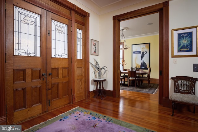 foyer entrance with ornamental molding and hardwood / wood-style floors