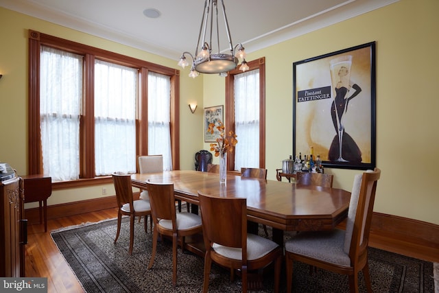 dining room featuring dark wood-type flooring, a wealth of natural light, crown molding, and a notable chandelier