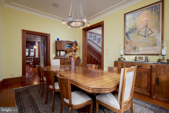 dining room featuring dark wood-type flooring, ornamental molding, and an inviting chandelier