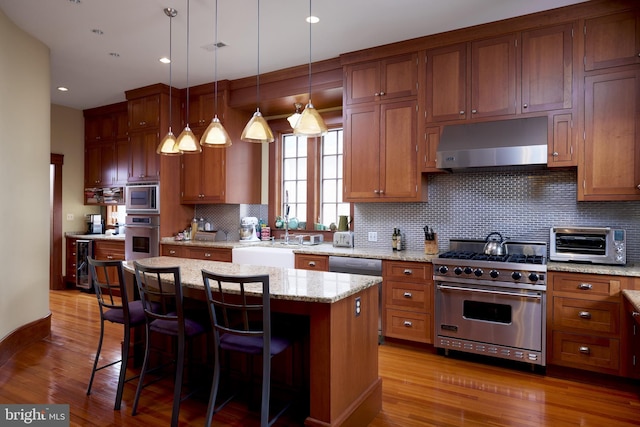 kitchen featuring a center island, sink, a kitchen breakfast bar, stainless steel appliances, and light stone counters